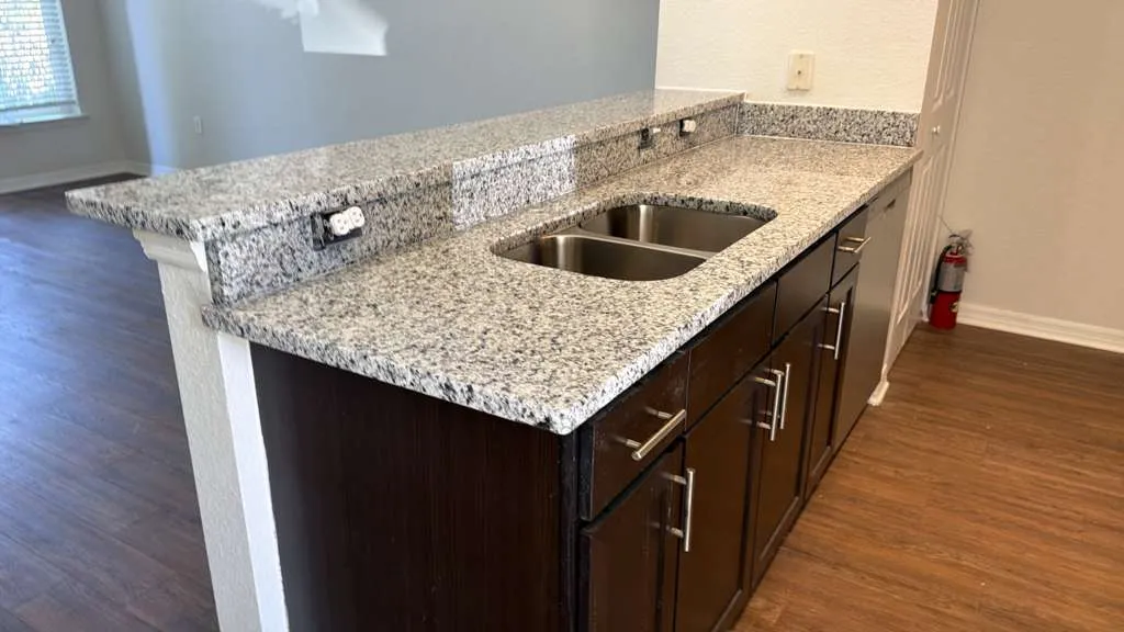 Speckled granite countertop with an undermount double sink and a breakfast bar