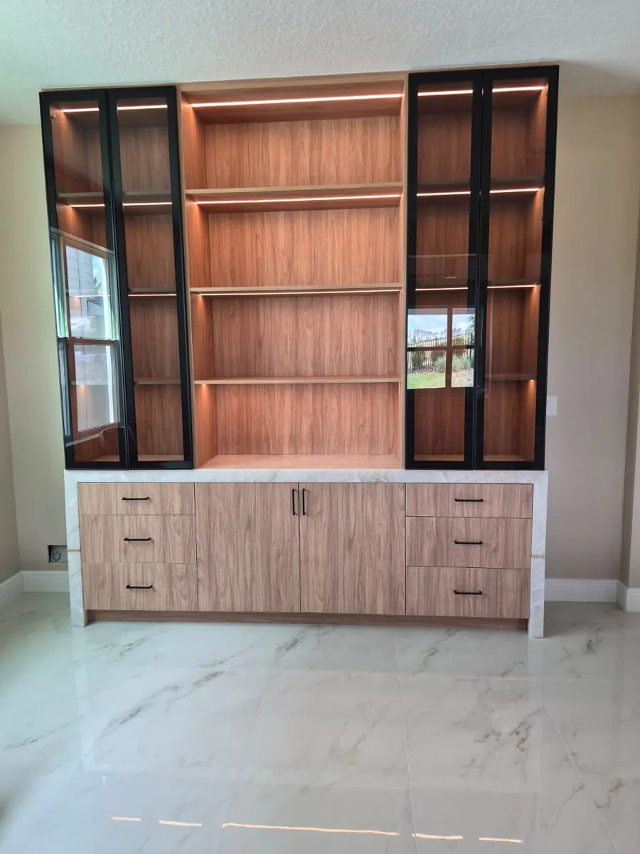 Built in wood shelving unit with lit shelves and lower cabinets